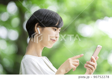 スマホで音楽を聴く若い女性　スマホを操作する若い女性　屋外 90752278