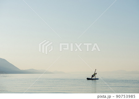 Young woman in yoga pose on sup board 90753985