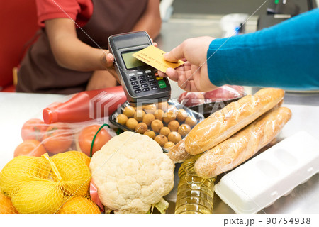Hand of male consumer holding credit card over screen of payment terminal Hand of male consumer holding credit card over screen of payment terminal 90754938