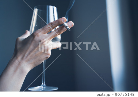 closeup of woman hands holding a cigarette and a wine glass 90755148