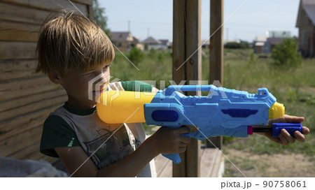 Boy play with water gun toy in garden. Boy play with water gun toy in garden. 90758061