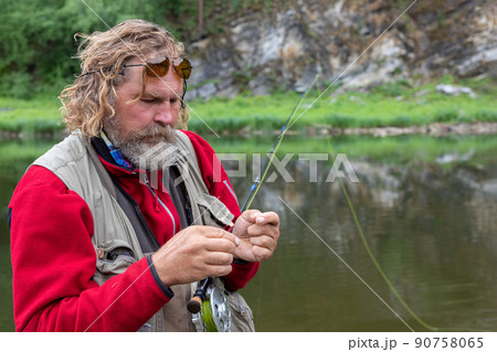 fly fishing fisherman in polarizing glasses mounts fly on fishing rod 90758065