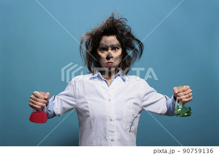 Mad and enranged scientist with wacky look infuriated by failed chemical experiment. Insane and angry chemist with dirty face and messy hair holding glass jars filled with toxic chemical compounds. Mad and enranged scientist with wacky look infuriated by failed chemical experiment. Insane and angry chemist with dirty face and messy hair holding glass jars filled with toxic chemical compounds. 90759136
