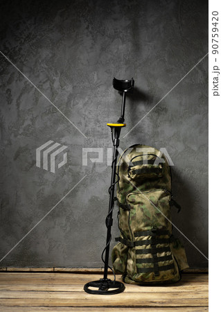 Metal detector and backpack on dark gray background 90759420
