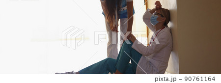 Exhausted medical worker after hard long surgery sitting on floor in hall Exhausted medical worker after hard long surgery sitting on floor in hall 90761164