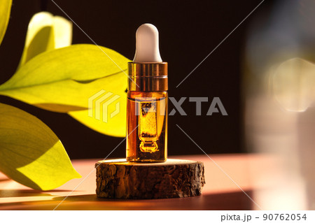 Cosmetic amber glass dropper bottle on wooden podium with oil, serum or fruit peeling in the sunlight. Green ruscus, soft focus. Beauty product presentation, natural background. Front. Mockup concept Cosmetic amber glass dropper bottle on wooden podium with oil, serum or fruit peeling in the sunlight. Green ruscus, soft focus. Beauty product presentation, natural background. Front. Mockup concept 90762054