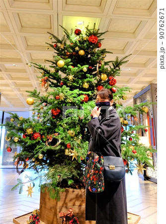 クリスマスツリーの前でポーズを取るマスク姿の女性 90762671