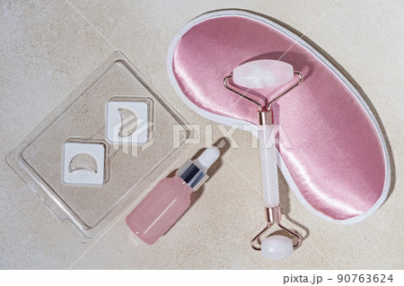 background for cosmetics product presentation with Dissolving Microneedle eye Patches, rose quartz massage roller, sleeping mask and  bottle of cosmetic oil or serum. evening routine before bedtime background for cosmetics product presentation with Dissolving Microneedle eye Patches, rose quartz massage roller, sleeping mask and  bottle of cosmetic oil or serum. evening routine before bedtime 90763624