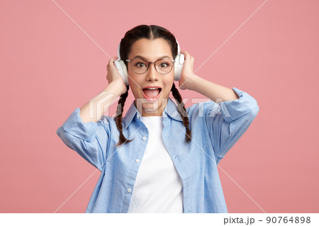 Cute Asian girl is wearing headphone and standing on pink background with happy face, blank copy space for your advertising content. Cute Asian girl is wearing headphone and standing on pink background with happy face, blank copy space for your advertising content. 90764898