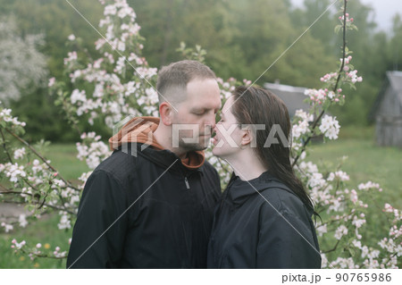 Sensual woman and man in cherry bloom. Couple in love in blossoming garden in spring. Love and romance, relationship, happy family outdoors 90765986
