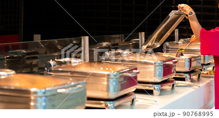 Woman taking food from heated trays in All-inclusive buffet in hotel restaurant 90768995