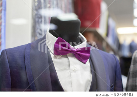 In the shop window is a mannequin in a formal suit and bow tie. In the shop window is a mannequin in a formal suit and bow tie. 90769483