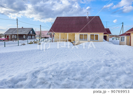 Snow-covered lawn in front of residential building in countryside. 90769953