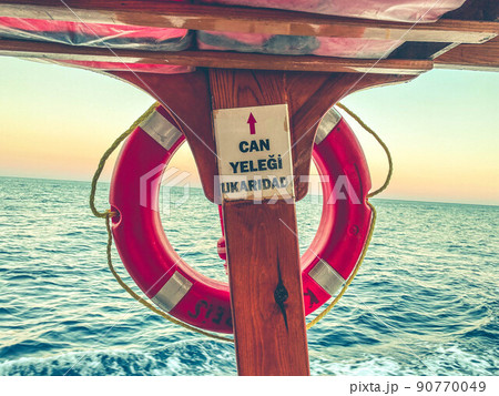 orange life buoy on the ship. cruise. to save passengers, an air circle made of rubber hangs. equipment under an awning against the background of the sea 90770049