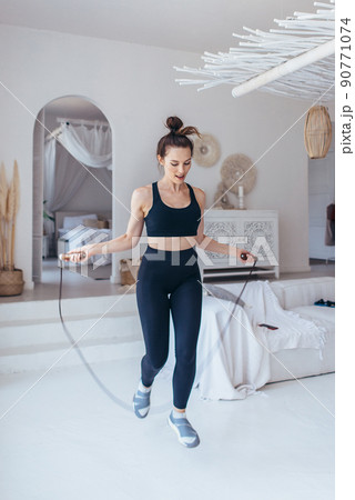 Fit woman skipping rope. Girl exercising with jumping rope at home. 90771074