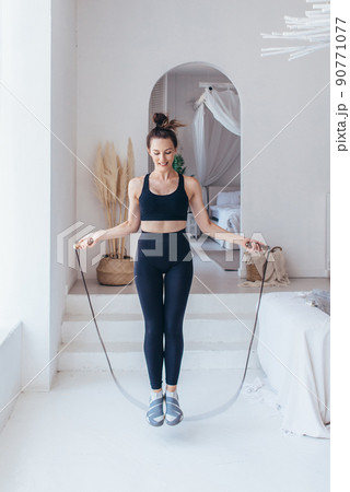 Fit woman with jump rope at home doing skipping workout. 90771077