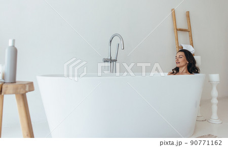 Woman resting in bathtub with eyes closed Woman resting in bathtub with eyes closed 90771162