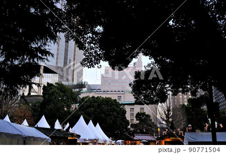 黄昏時の日比谷公園で行われたクリスマスマーケットと高層ビル群の風景 90771504