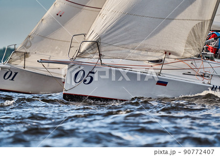 Bowsprits of sailing yachts in sailing regatta at sunset, still water, the clear sky, hot racing 90772407