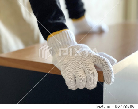 チェストを移動させる軍手をはめた手元 90773686