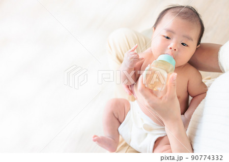 ミルクを飲む赤ちゃん　メロイックサイン　生後1ヶ月　コピースペース　 90774332
