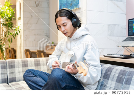 白いエレキギターを弾く若い男性 白いエレキギターを弾く若い男性 90775915