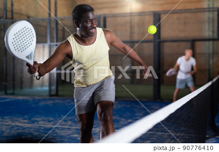 Sporty afro american man playing padel tennis indoor 90776410