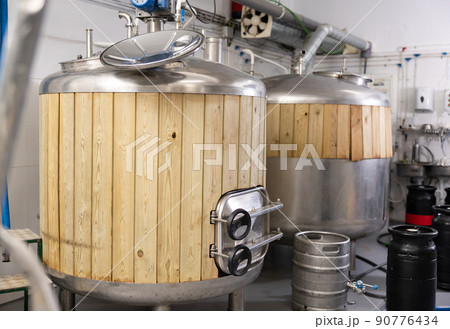 Steel fermenters with wood trim and kegs in brewery Steel fermenters with wood trim and kegs in brewery 90776434