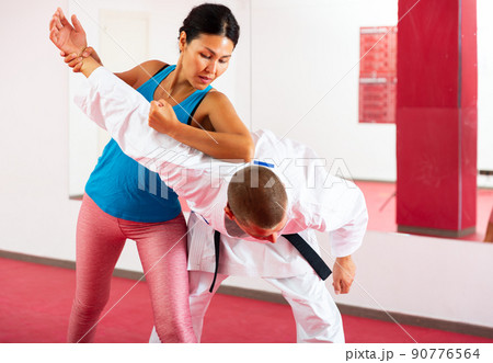 Asian woman with her instructor are training self-defence moves in sport gym 90776564