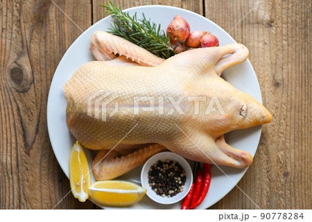raw duck with spices ready to cook on wooden background , fresh duck meat on plate for food , whole duck and lemon rosemary chili garlic - top view raw duck with spices ready to cook on wooden background , fresh duck meat on plate for food , whole duck and lemon rosemary chili garlic - top view 90778284