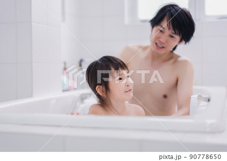 小さな娘と一緒にお風呂に入るお父さん 90778650