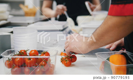A chef working in the kitchen. Cutting the cherry tomatoes A chef working in the kitchen. Cutting the cherry tomatoes 90779193