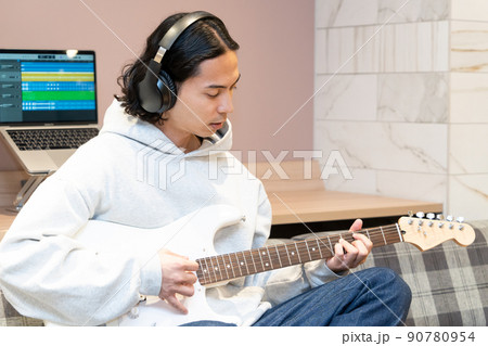 白いエレキギターを弾く若い男性 90780954