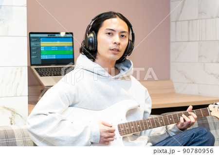 白いエレキギターを弾く若い男性 90780956