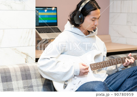 白いエレキギターを弾く若い男性 90780959