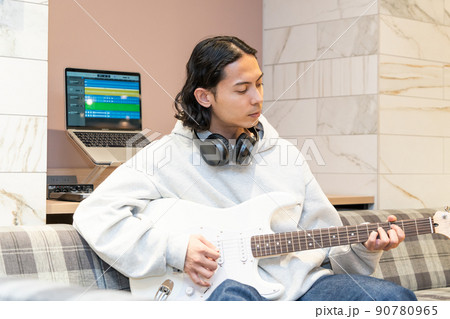 白いエレキギターを弾く若い男性 90780965