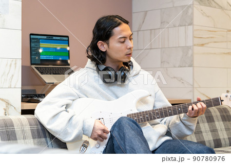 白いエレキギターを弾く若い男性 90780976
