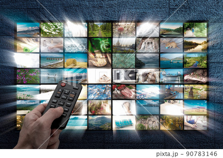 Online Multimedia video concept on TV set in dark room. Man watching online TV with remote control in hand. Multimedia streaming VoD content provider. Video on demand screen with remote control 90783146