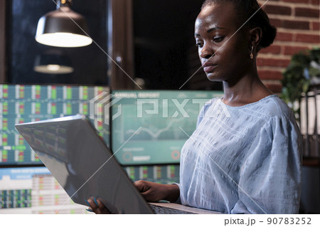 Hedge fund company employee standing in front of workstation with laptop looking at real time market data. Investment agency professional trader analyzing financial chart live on computer. Hedge fund company employee standing in front of workstation with laptop looking at real time market data. Investment agency professional trader analyzing financial chart live on computer. 90783252