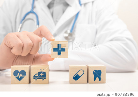 Healthcare and Insurance concept. Doctor hand choose cross sign on wood cube block. Health care insurance or service concept. Medical healthcare icons on stacked wooden cubes Healthcare and Insurance concept. Doctor hand choose cross sign on wood cube block. Health care insurance or service concept. Medical healthcare icons on stacked wooden cubes 90783596