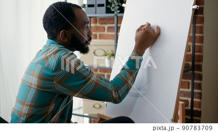 Young artist drawing vase masterpiece with pencil on canvas, learning new artistic skills in art workshop class. Student using crafting equipment to create design at lesson practice. 90783709