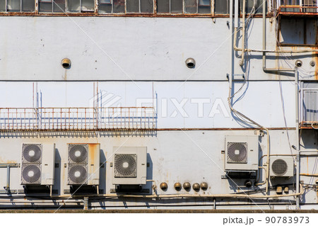 ビルの壁に取り付けられた空調機の室外機 90783973
