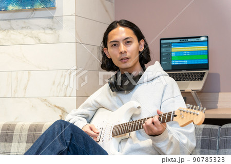 白いエレキギターを弾く若い男性 90785323