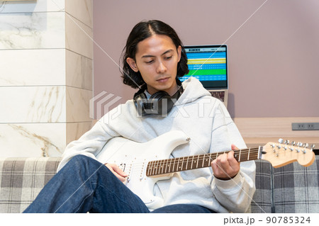 白いエレキギターを弾く若い男性 90785324