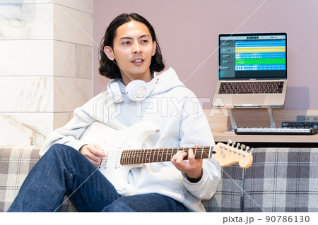 白いエレキギターを弾く若い男性 90786130