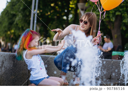 Mother and daughter having fun on girl birthday splashing near city fountain 90786516