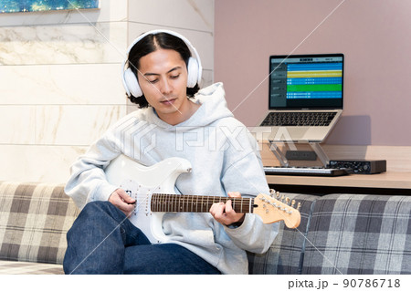 白いエレキギターを弾く若い男性 90786718