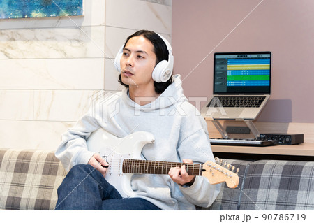 白いエレキギターを弾く若い男性 90786719