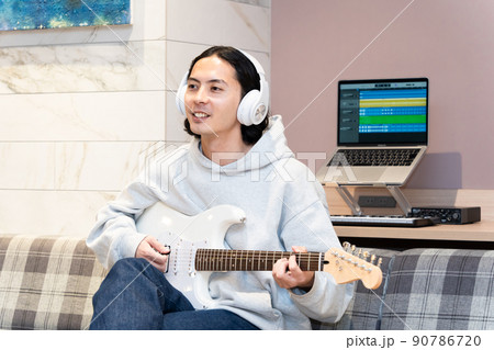 白いエレキギターを弾く若い男性 90786720