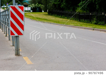 red and white diagonal striped sign at road fence end red and white diagonal striped sign at road fence end 90787496